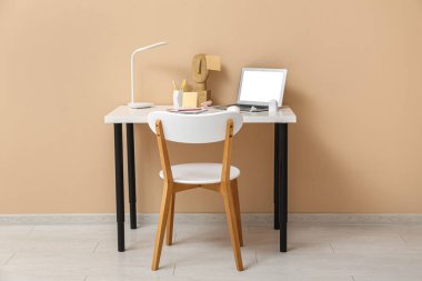 Ofisteki masada dizüstü bilgisayar, kablosuz kulaklık, lamba ve defter.