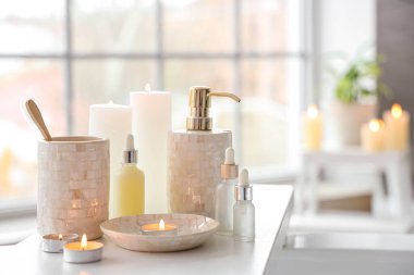 Diş fırçaları, mumlar ve beyaz küvet tepsisindeki farklı kozmetikler.