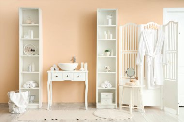 Lavabosu ve raf üniteleri olan şık bir banyo.