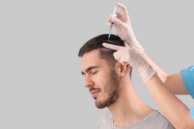 Genç adam arka planda saç büyümesi için iğne oluyor, yakın plan.