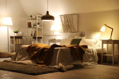 Yatak odasının içinde, yatakta ekoseli ve geceleri parlayan lambalar.