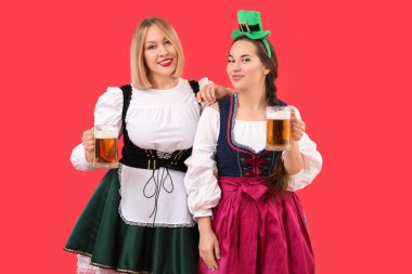Kırmızı arka planda Aziz Patrick Günü 'nü kutlayan biralı mutlu kadınlar