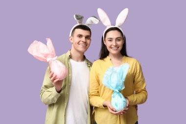 Paskalya hediyeleri ve leylak arka planda tavşan kulaklı mutlu genç çift.