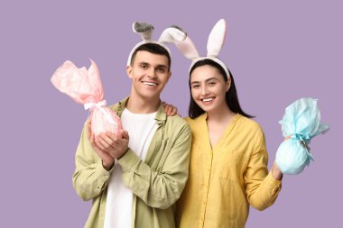 Paskalya hediyeleri ve leylak arka planda tavşan kulaklı mutlu genç çift.