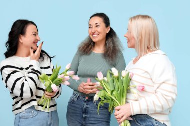 Mavi arka planda güzel lale buketleri ve parfümlü olgun kadınlar. Uluslararası Kadınlar Günü