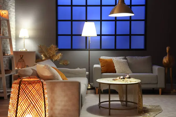 Interiér Stylového Obývacího Pokoje Zlatou Výzdobou Svítícími Lampami Pohovkami Noci — Stock fotografie