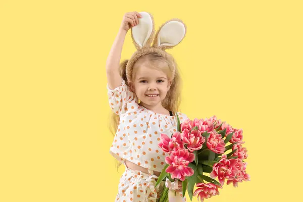 可爱的小女孩 长着小兔子耳朵 黄色背景上的郁金香花 复活节庆祝活动 — 图库照片