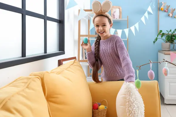 Aranyos Kislány Nyuszifülekkel Húsvéti Tojásokat Rejteget Párna Mögött Kanapén Otthon — Stock Fotó