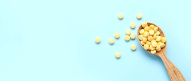 Mavi arka planda sarı haplı ahşap kaşık ve metin için yer var.