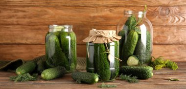 Taze ve konserve salatalıklı kavanozlar ahşap arka planda