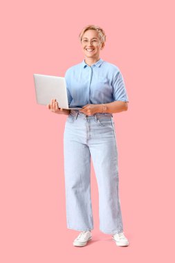 Pembe arka planda dizüstü bilgisayarı olan olgun bir kadın programcı.