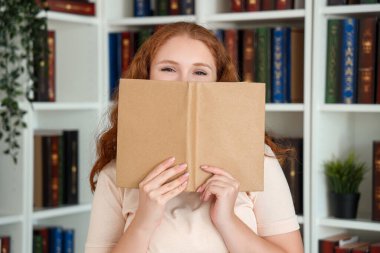Kütüphanede kitap okuyan genç bir kadın.