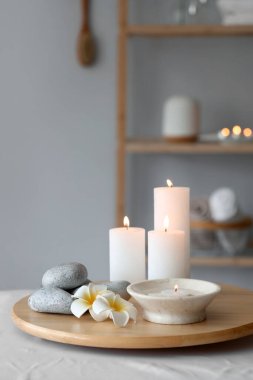 Kaplıca salonundaki kanepede taş ve çiçeklerle mum yakmak, yakın çekim.