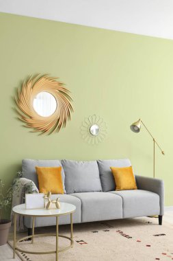 Oturma odasının iç tarafında yastıkları ve kahve masası olan rahat gri bir kanepe.