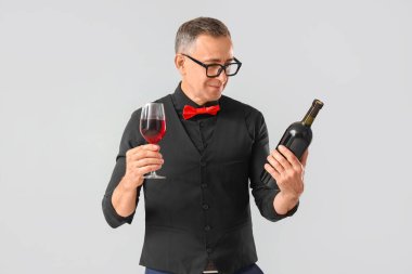 Hafif arka planda cam ve bir şişe kırmızı şarapla olgunlaşmış şarap garsonu.