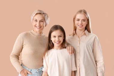 Bej arka planda annesi ve büyükannesi olan küçük bir kız.