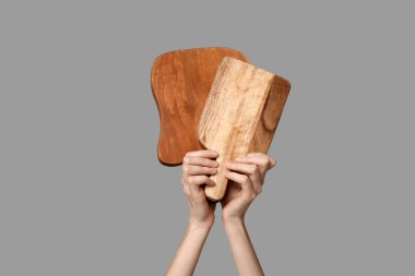 Gri arka planda tahta kesme tahtaları olan kadın elleri