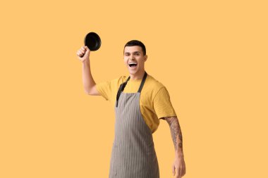 Sarı arka planda tavası olan yakışıklı bir genç adam portresi.