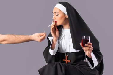 Arka planda sigara yakan şarap kadehli seksi rahibe.