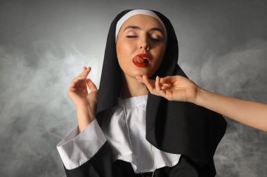 Kadın eli ve siyah arka planda sigara içen seksi bir rahibe.