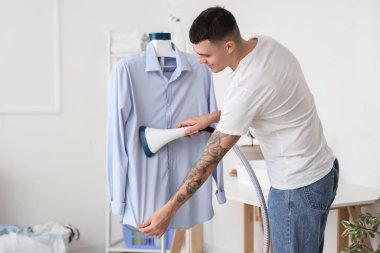 Evdeki mavi gömlekli mutlu genç adam.