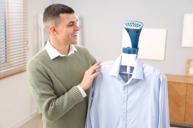 Evdeki mavi gömlekli mutlu genç adam.