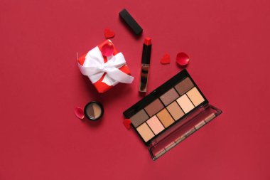 Kırmızı arka planda kozmetik ürünleri ve kalpleri olan hediye kutusu. Sevgililer Günü kutlaması