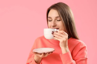 Güzel genç bayan pembe arka planda çay içiyor, yakın plan.