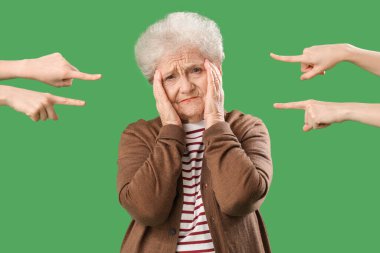 People pointing at upset senior woman on green background. Accusation concept clipart