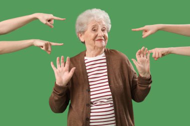 People pointing at senior woman on green background. Accusation concept clipart