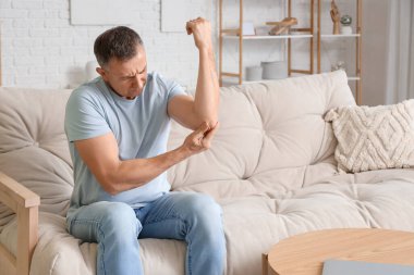 Evde kol ağrısı çeken olgun bir adam.