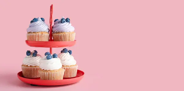 stock image Tasty cupcakes with blueberries on stand against pink background with space for text