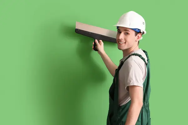 緑の背景にパティナイフを塗った男性労働者 — ストック写真
