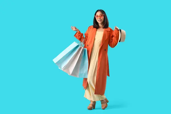 幸せな美しい若いですアジアの女性でショッピングバッグ上の青の背景 — ストック写真