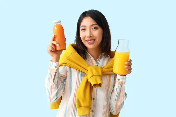 青い背景にジュースのボトルが付いている美しいアジアの女性 — ストック写真