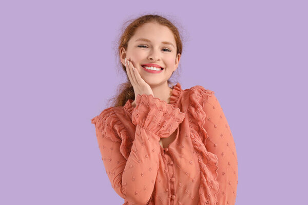 Smiling young redhead woman on lilac background