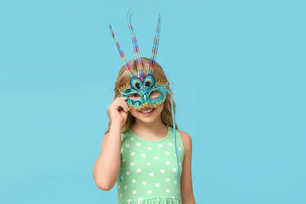 青い背景にカーニバルマスクを着用するかなり小さな少女 ストックフォト