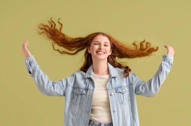 Yeşil arka planda gülümseyen kızıl saçlı bir kadın.