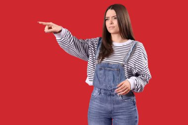 Genç bir kadın kırmızı arka plandaki bir şeyi işaret ediyor. Suçlama kavramı