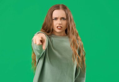 Yeşil arka plandaki izleyiciye bakan genç bir kadın. Suçlama kavramı