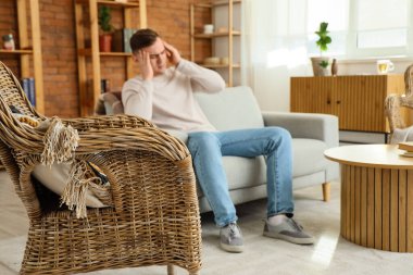 Genç adam evdeki kanepede baş ağrısından muzdarip.