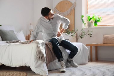 Yatak odasında karın ağrısı çeken genç bir adam.