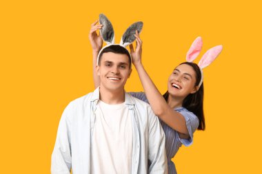 Sarı arka planda Paskalya tavşanı kulakları olan mutlu genç çift.