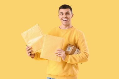 Sarı arka planda paketleri olan bir erkek çevrimiçi mağaza satıcısı