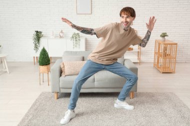 Evde dans eden dövmeli genç adam.