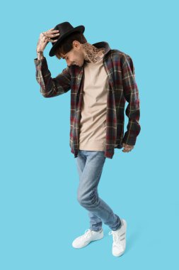 Mavi arka planda dans eden dövmeli genç adam.