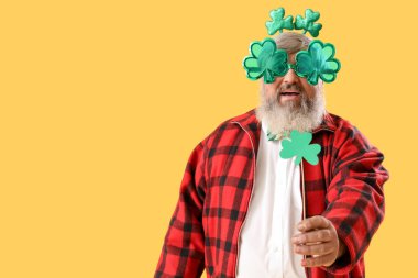 Sarı arka planda yoncaları olan olgun bir adam. Aziz Patrick Günü kutlaması