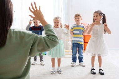 Anaokulunda egzersiz yapan anaokulu öğretmeni olan küçük çocuklar.