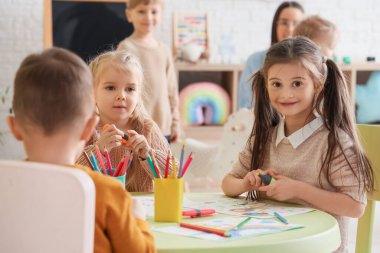 Anaokulundaki masada resim yapan küçük kızlar.