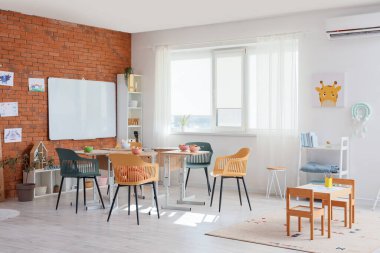 Masaların üzerinde kahvaltı olan anaokulu.